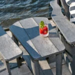 T04 Addy Side Table in Slate Grey in between two Adirondack armrests on a dock